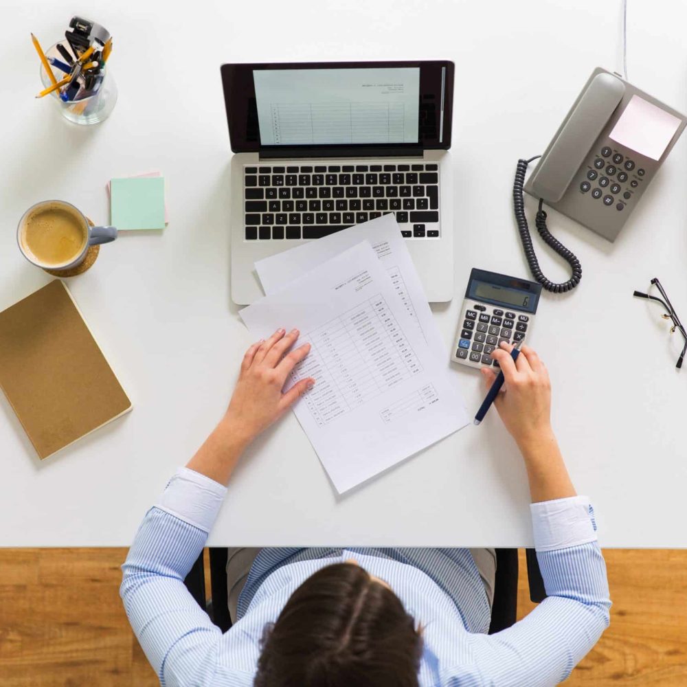 business, accounting, people and technology concept - businesswoman with laptop computer, calculator and papers working at office